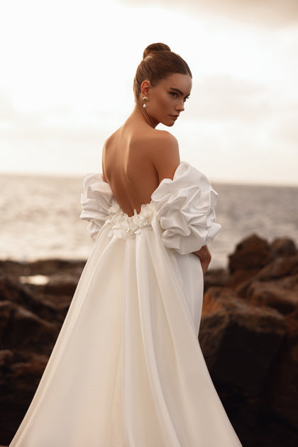 Backless bridal gown with statement puff sleeves and floral details for a designer bridal style.