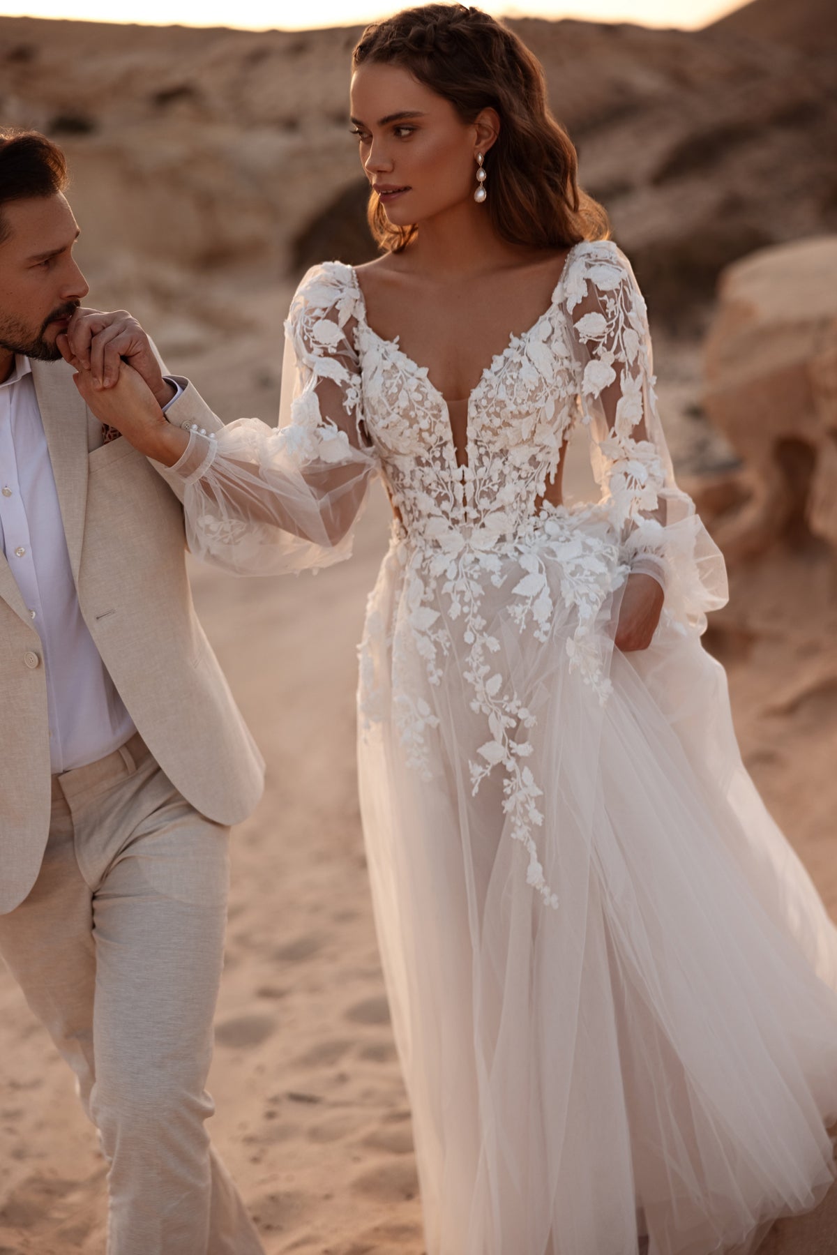 Front view of a bride in Alia beside the groom, with 3D floral lace at the deep V-neckline