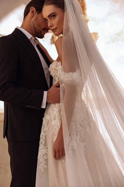 A close-up of Ariella’s off-shoulder sleeve features delicate lace appliqués, adding to the gown’s graceful and romantic feel.