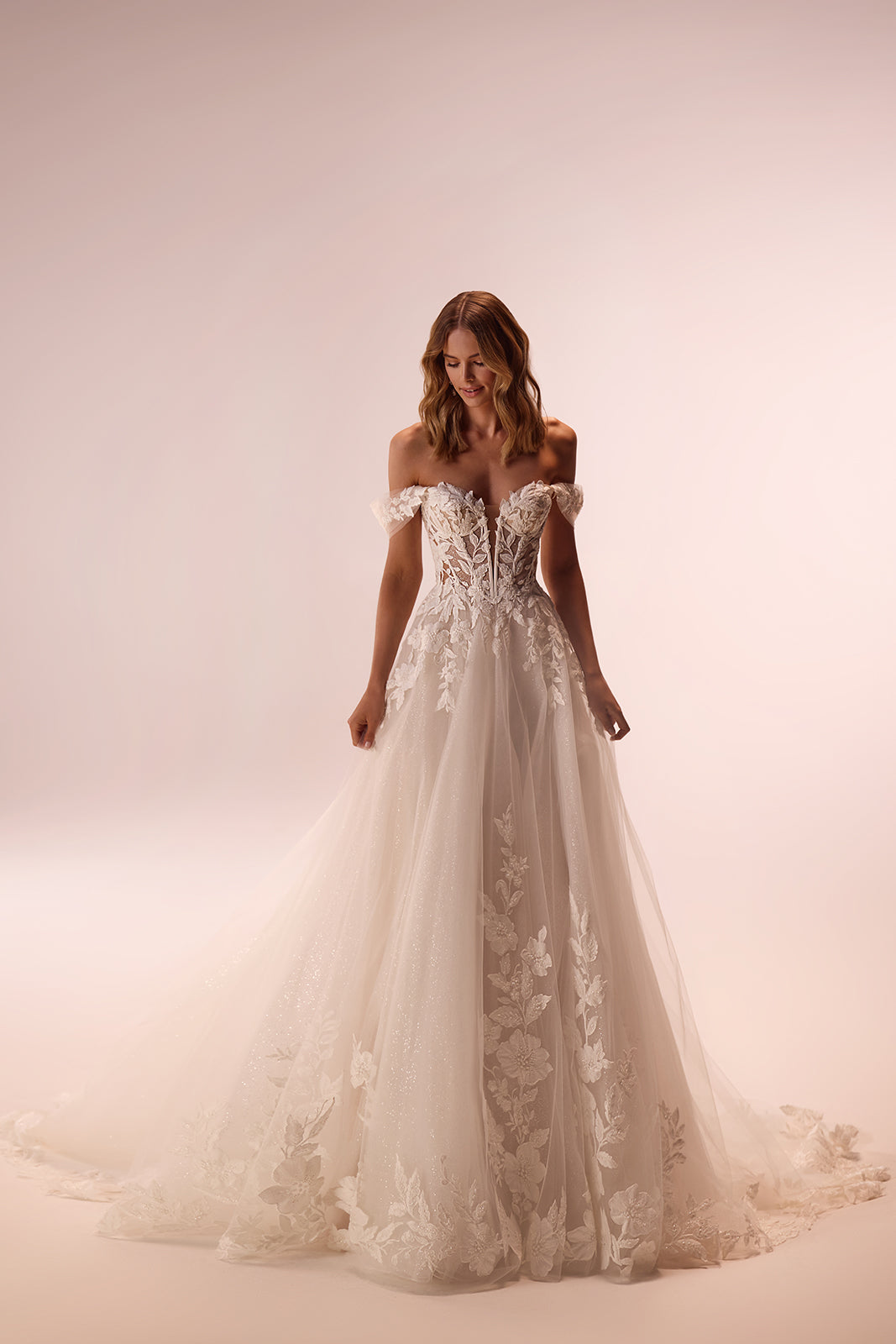 Studio view of Aurora wedding dress in full length, with lace appliqués on a glittering tulle skirt
