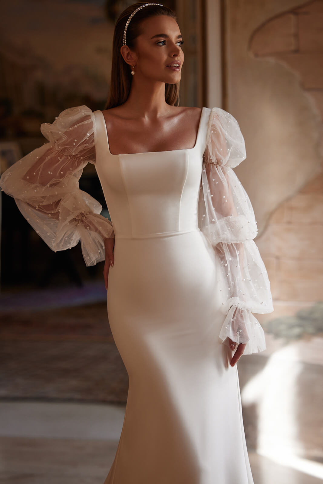 Clara wedding dress from the side, with a square neckline and sheer puff sleeves