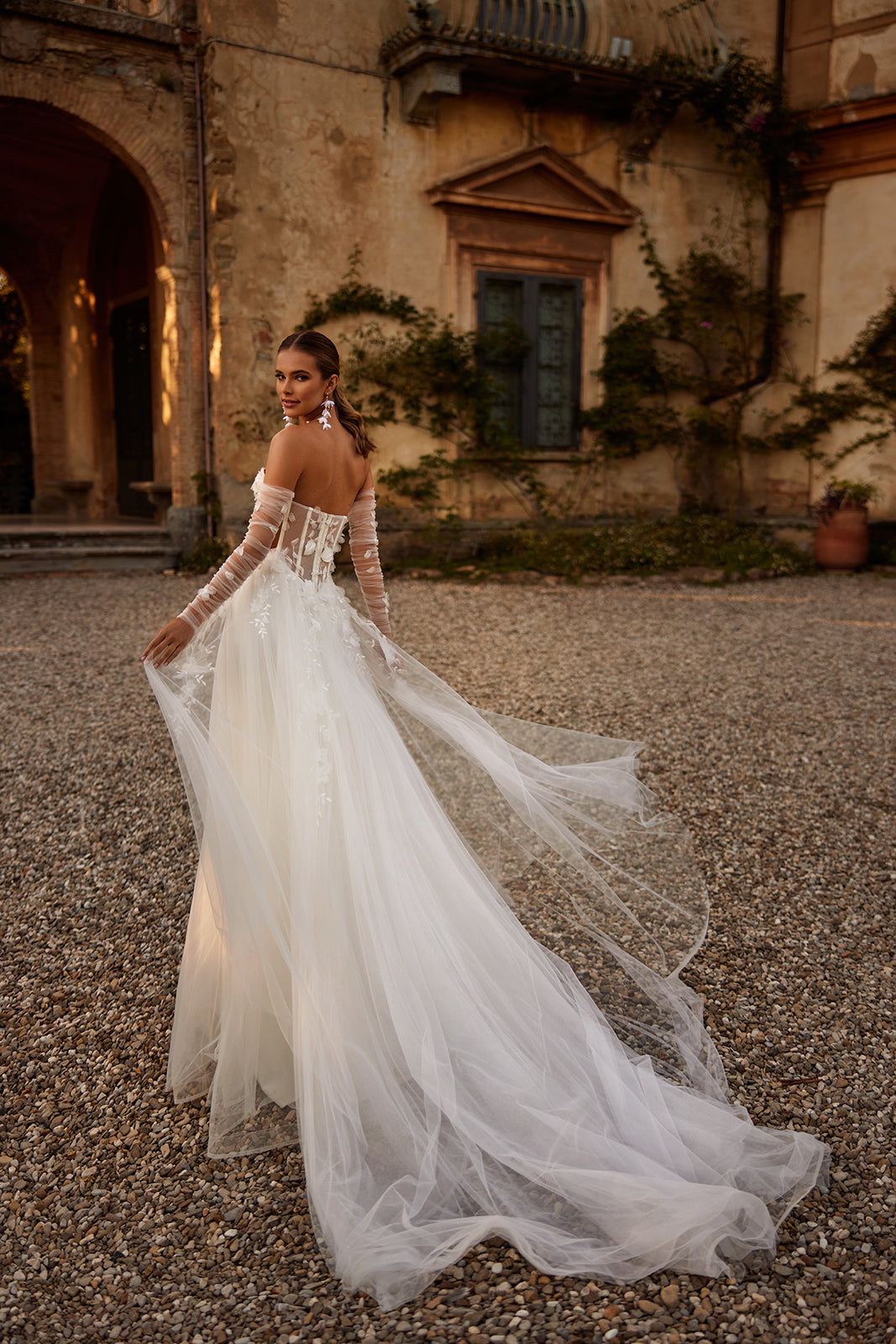 Ilimaris wedding dress in motion before a villa, with an A-line tulle skirt and train