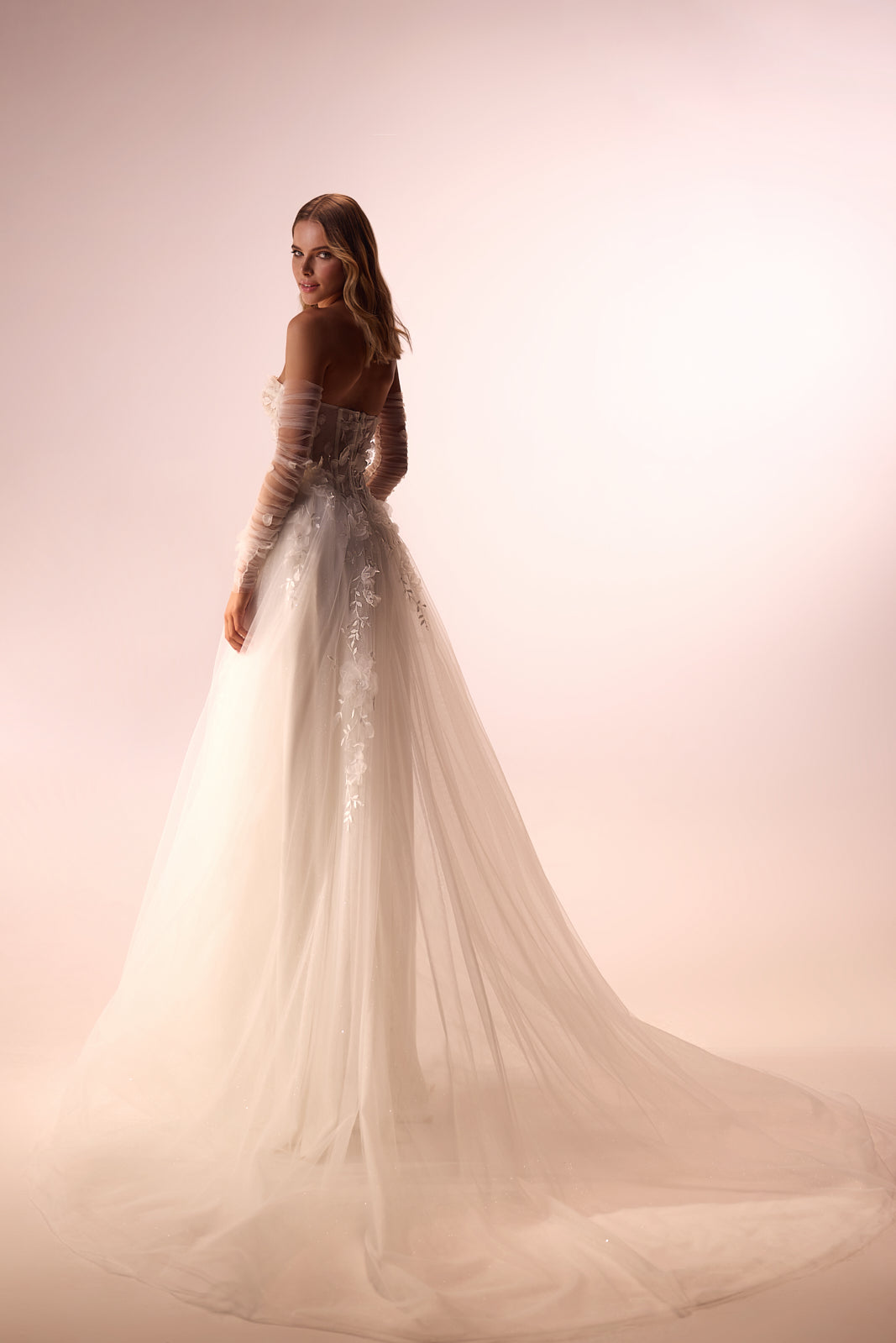 Studio back view of Ilimaris wedding dress, with a long tulle skirt flowing into a soft train