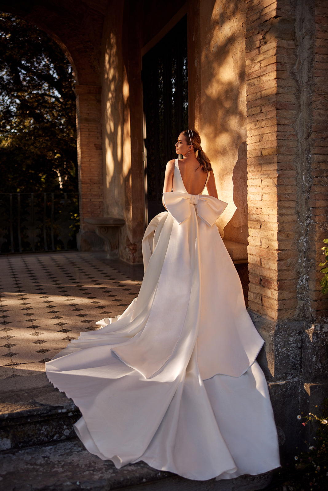 Back view of Margo wedding dress in a loggia, with a large satin bow above its train