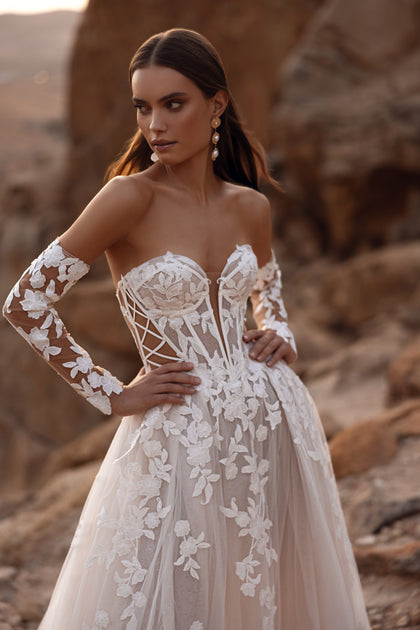 The Nabila bridal gown with a long lace veil and floral embroidery captures the essence of romance and sophistication.