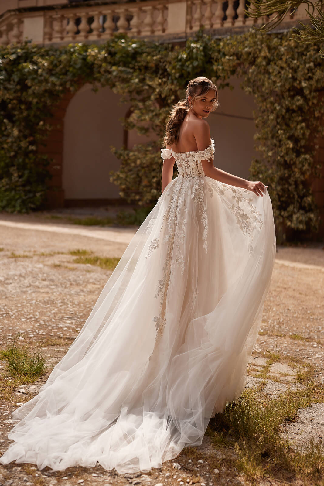 Floral lace crosses the tulle skirt and train of Mia diagonally in this back view