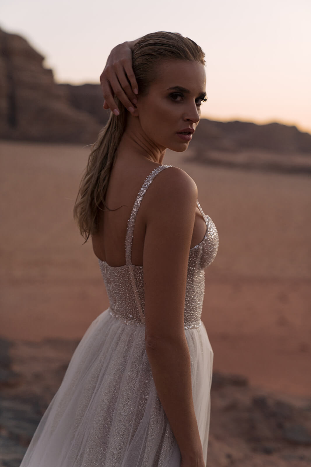 Three-quarter view of Inca wedding dress, hand in the hair above fine beaded straps and the corset back