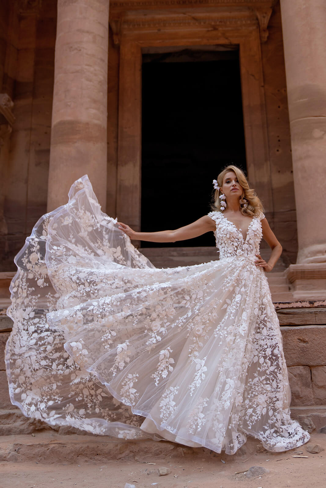 Azalea wedding dress in motion before an arch, its lace train lifting