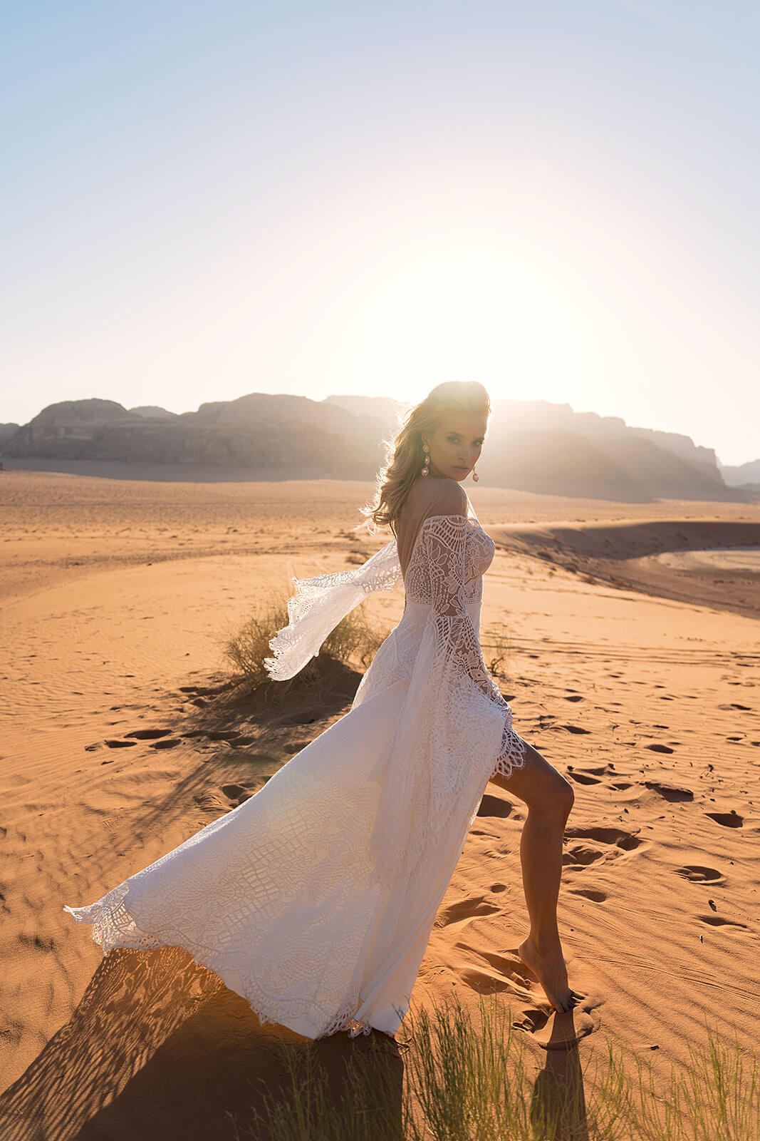 Full-length Lea A-line lace wedding dress in the desert, sleeves and skirt blowing in the wind