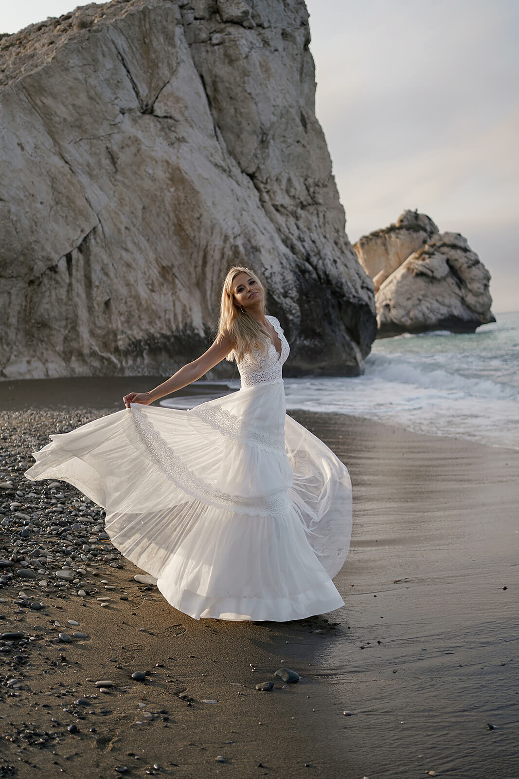 Lidia wedding dress at the water's edge, with the light skirt swirling to one side