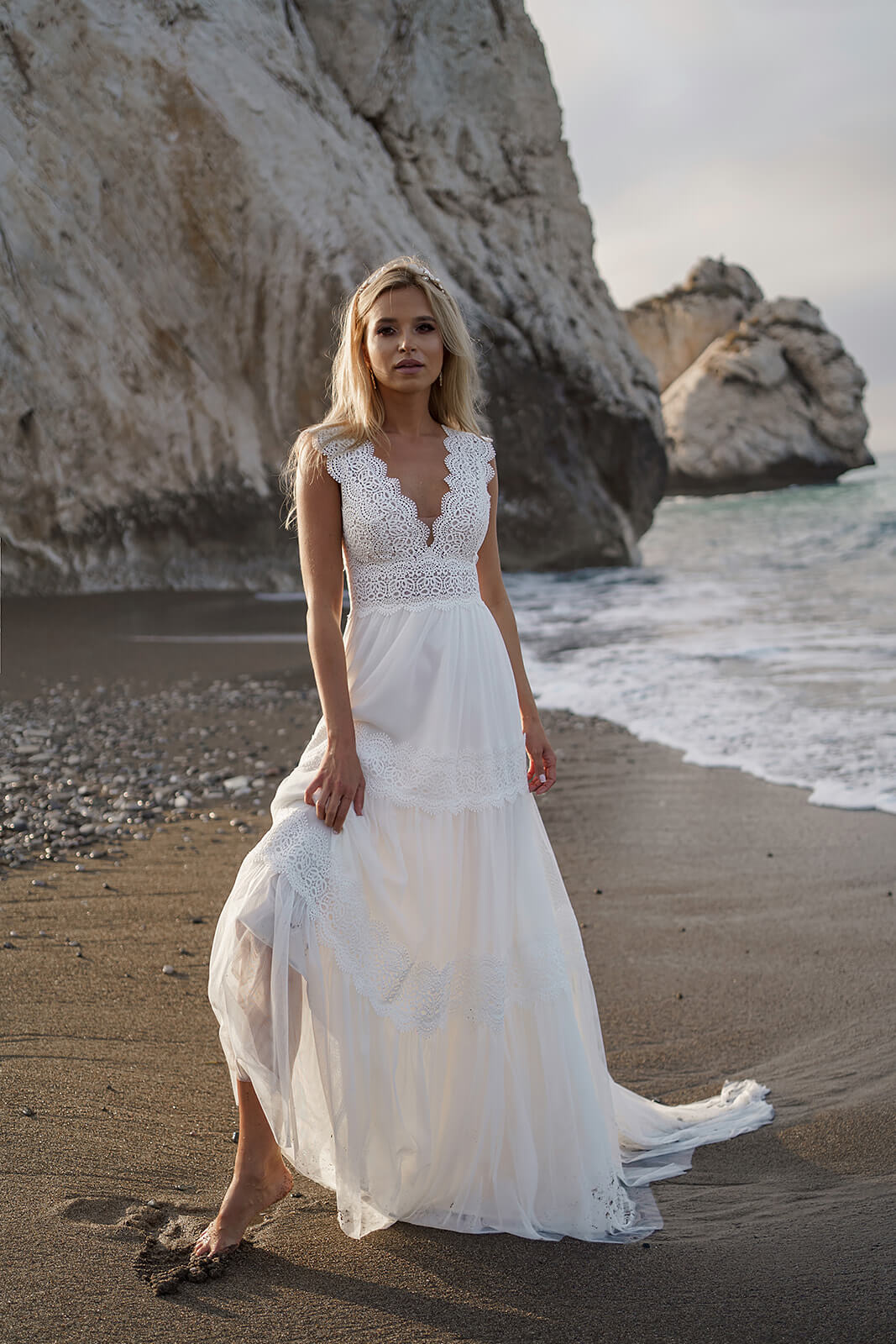 Full-length front view of Lidia wedding dress on wet sand, with a light trailing skirt