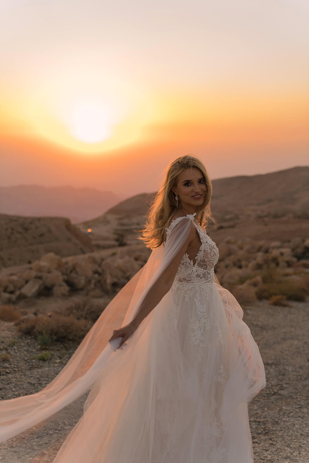 Three-quarter back view of Linda wedding dress at sunset, with an A-line lace skirt