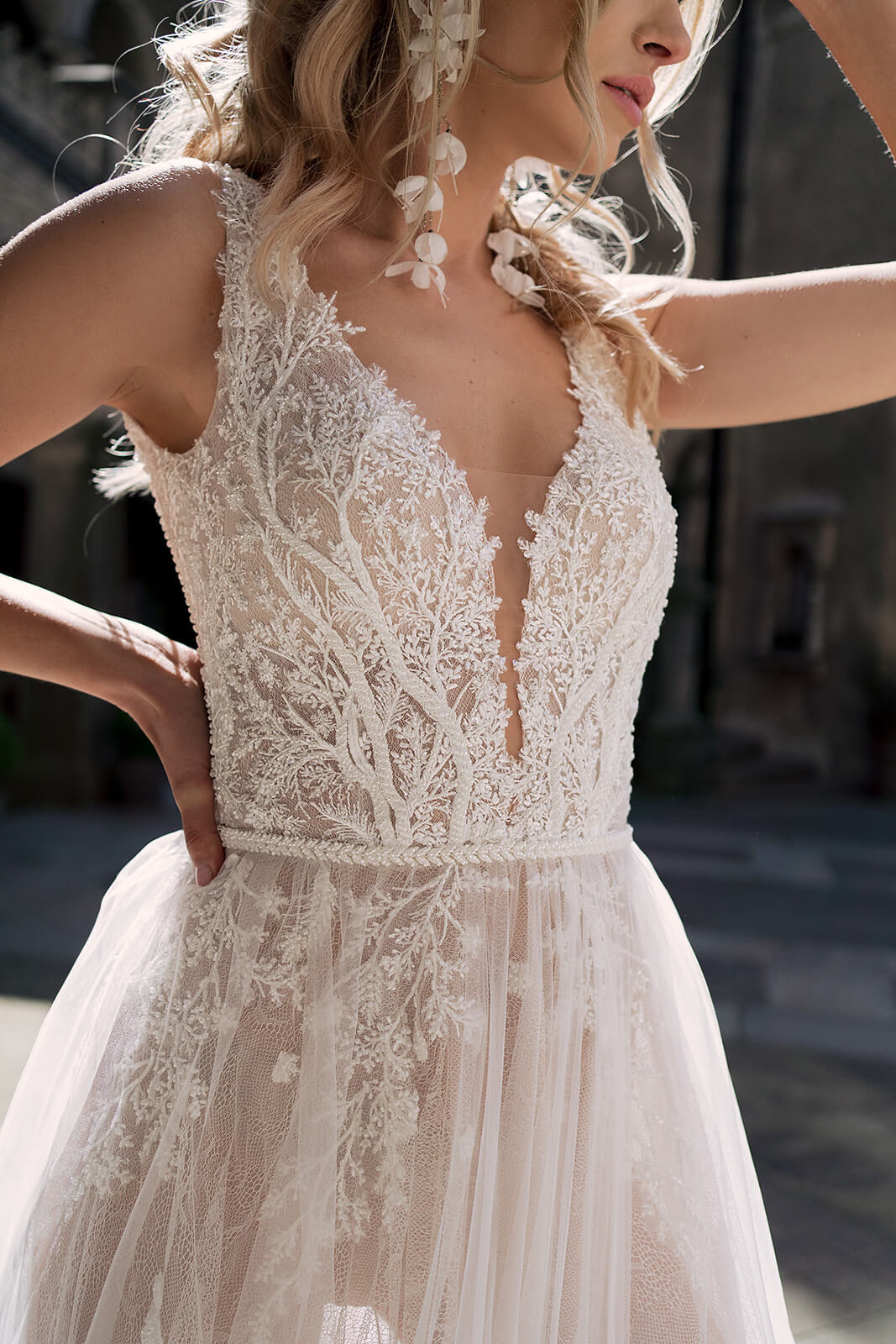 Livia wedding dress in close-up with arms raised, showing the lace bodice and beaded belt