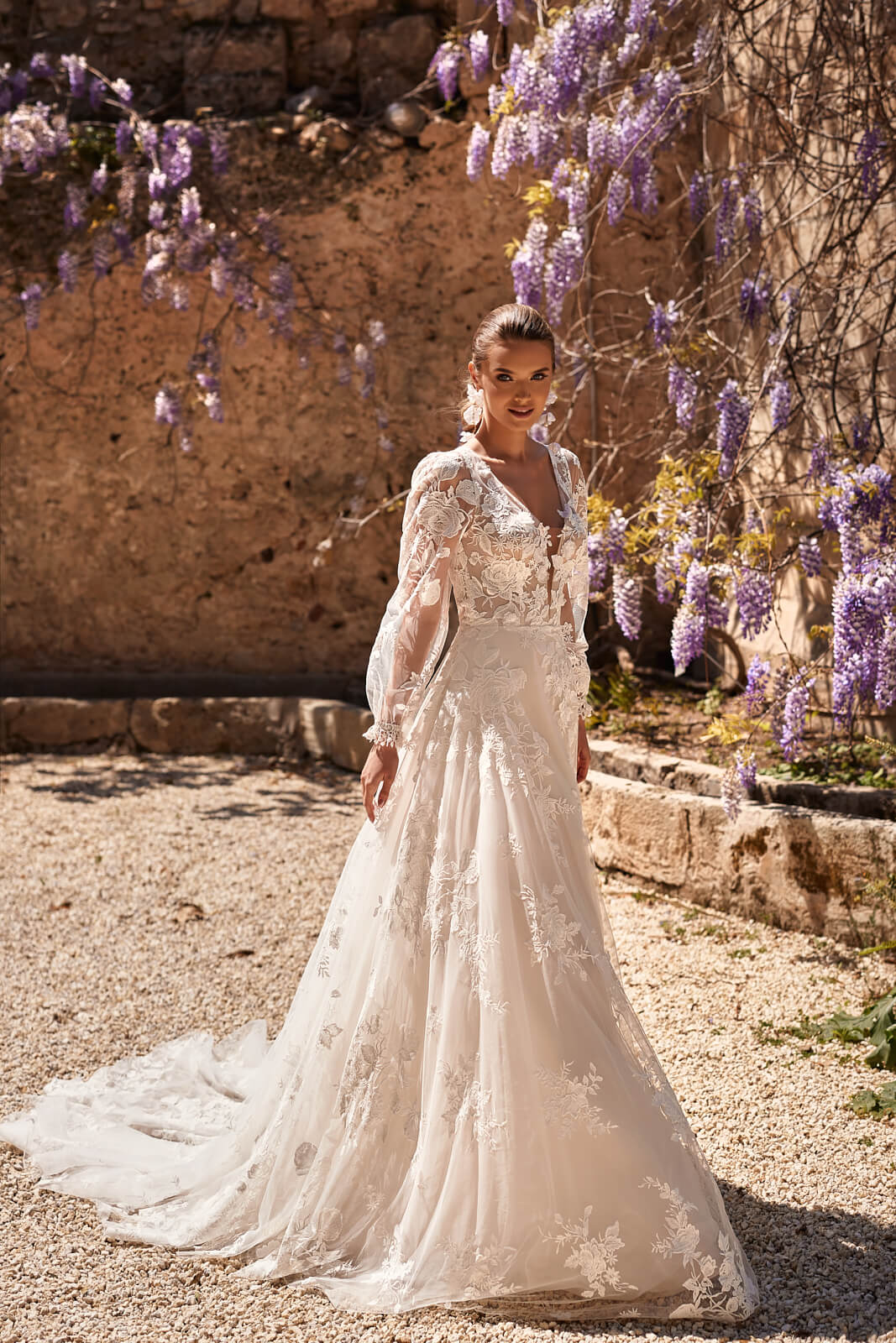 Asami wedding dress from the front beneath flowering wisteria, with floral lace and long sleeves