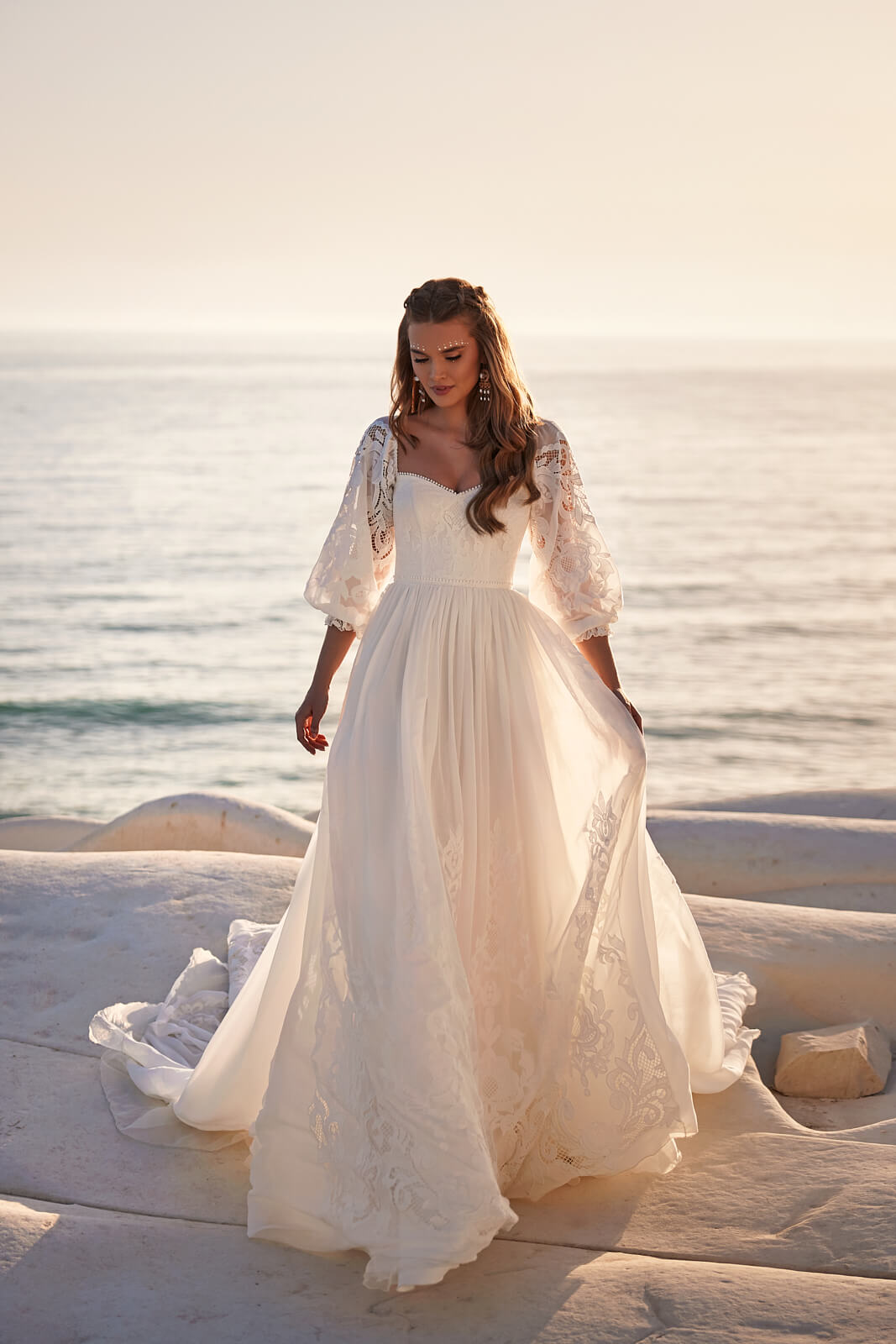 Full-length front view of Rania beside the water, with lace panels along the skirt