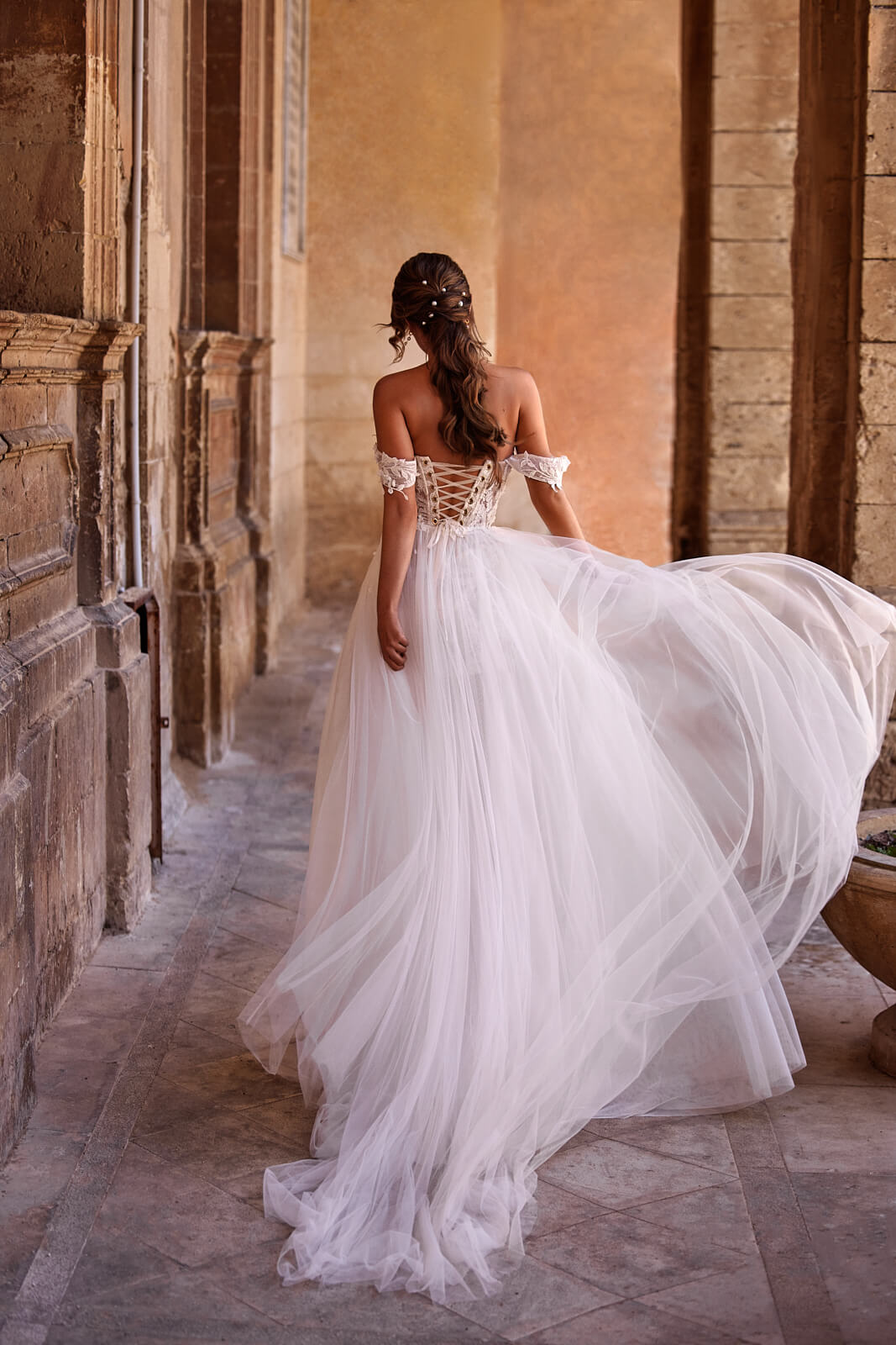 Lace-up corset above the full tulle overskirt of Noa, seen from behind