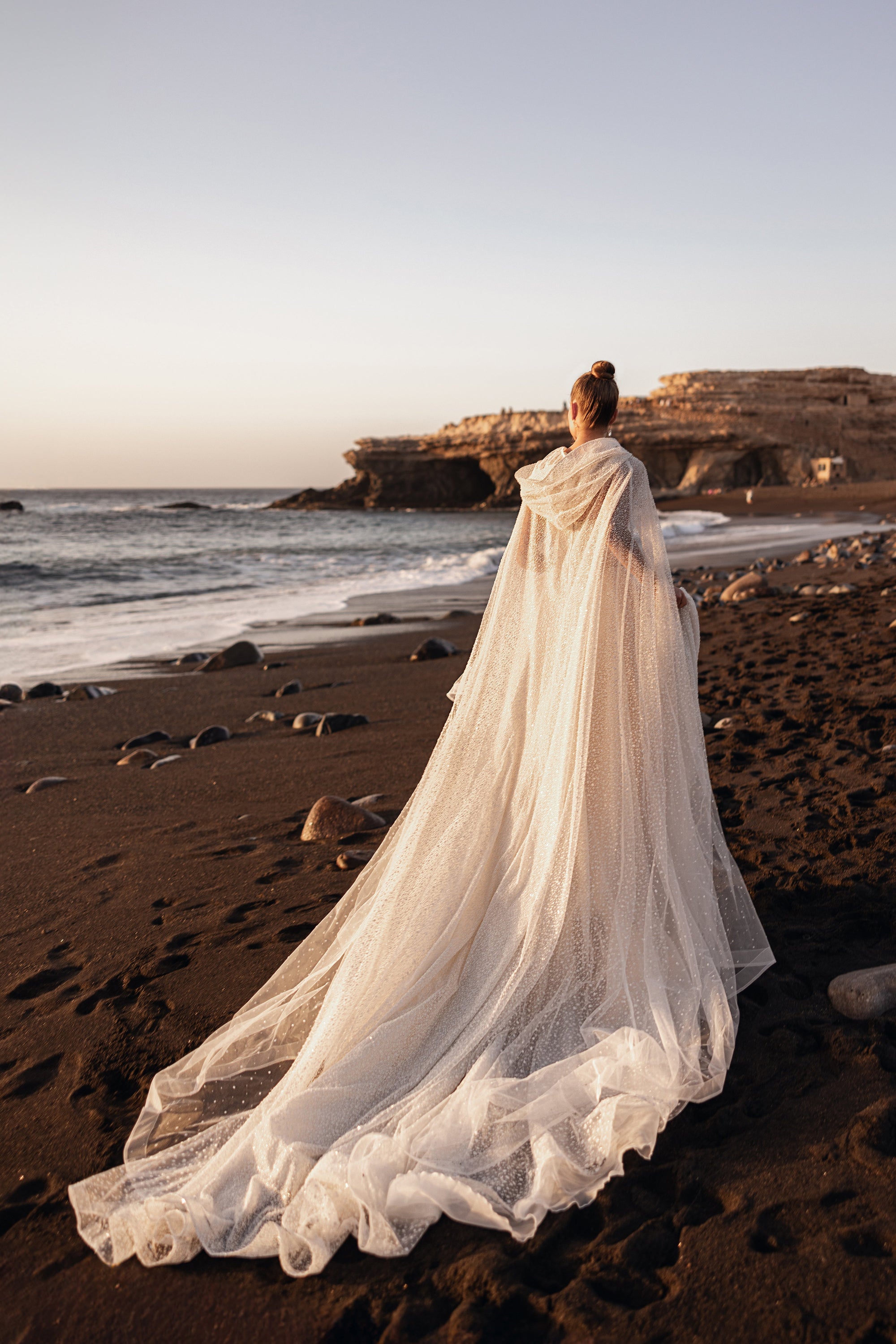 Amira bridal cape with long tulle train and delicate appliqués, perfect for beach weddings and modern brides.