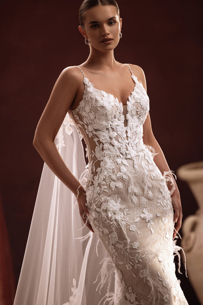The Aspasia bridal dress features a long lace train and floral-detailed cape for an ethereal, romantic finish.