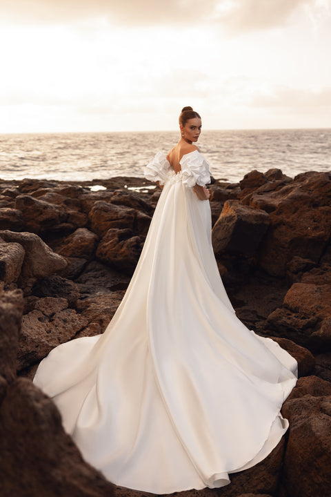 Backless bridal dress with an extended flowing train, perfect for coastal wedding photography.