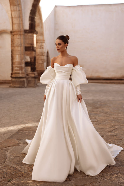 Graceful off-the-shoulder satin bridal gown Anika featuring voluminous sleeves and delicate floral details.