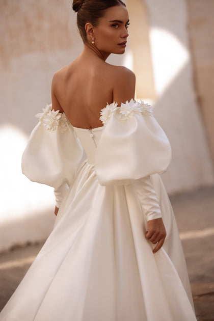 Contemporary bridal gown Anika with statement puff sleeves and floral embellishments for a romantic flair.