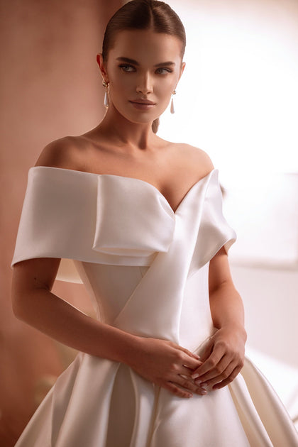 The Avin bridal gown’s button-down back and off-shoulder cut create an elegant, feminine silhouette.
