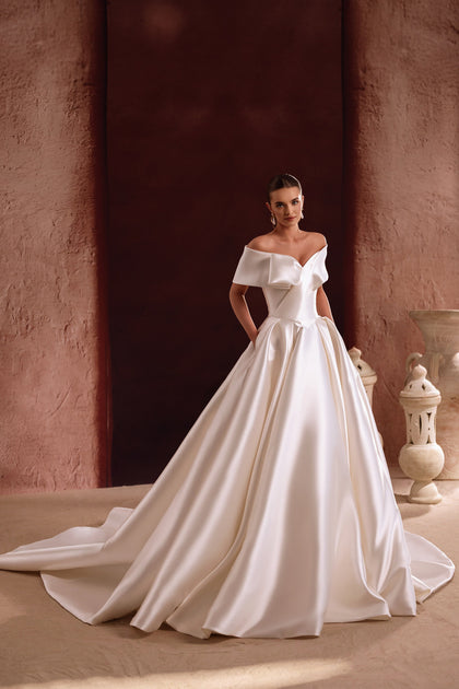 The Avin bridal gown features an off-shoulder satin neckline and structured bodice for a refined, elegant look.