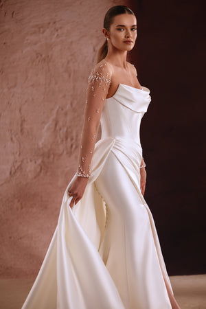 The Aylin bridal gown with pearl-detailed illusion sleeves and a softly draped neckline exudes modern sophistication.