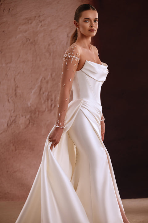 The Aylin bridal gown with pearl-detailed illusion sleeves and a softly draped neckline exudes modern sophistication.