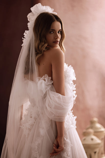 The Bella bridal dress close-up highlights the 3D floral corset and translucent tulle, exuding contemporary romance.