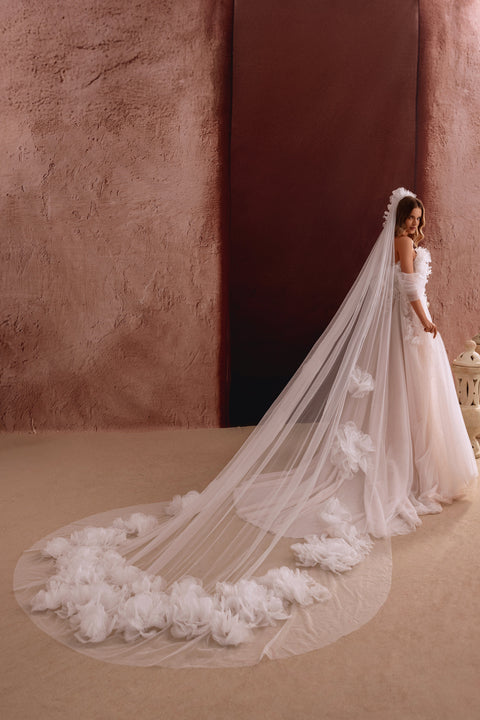 The Bella wedding gown with a thigh-high slit and floral appliqués combines sensual elegance with airy romance.
