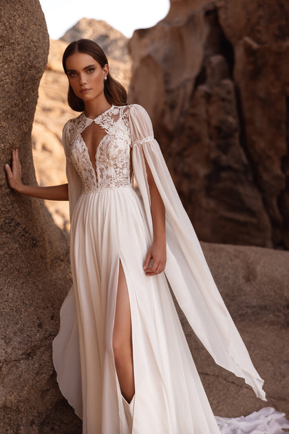 The Etra bridal gown highlights delicate lacework and airy sleeves, blending vintage charm with contemporary style.
