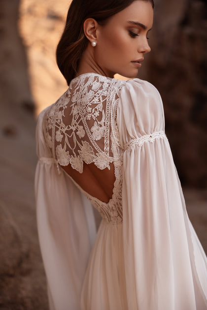 The Etra bridal dress with lace-back detailing and long chiffon train radiates ethereal grace and timeless romance.