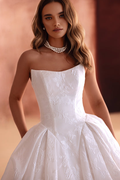 The Hebe bridal gown showcases a strapless corset and floral jacquard pattern, offering classic elegance for the modern bride.