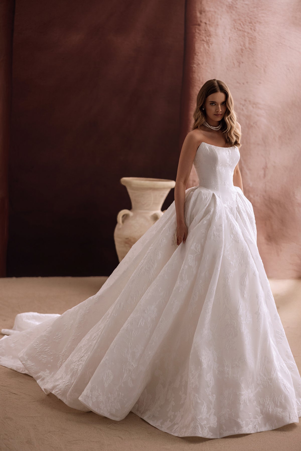 The Hebe bridal gown with a long cathedral train and strapless bodice creates a fairytale-inspired wedding look.