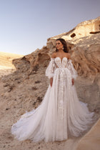 The Huda bridal gown with off-the-shoulder neckline, floral appliqué and corset detailing embodies romantic bohemian elegance.
