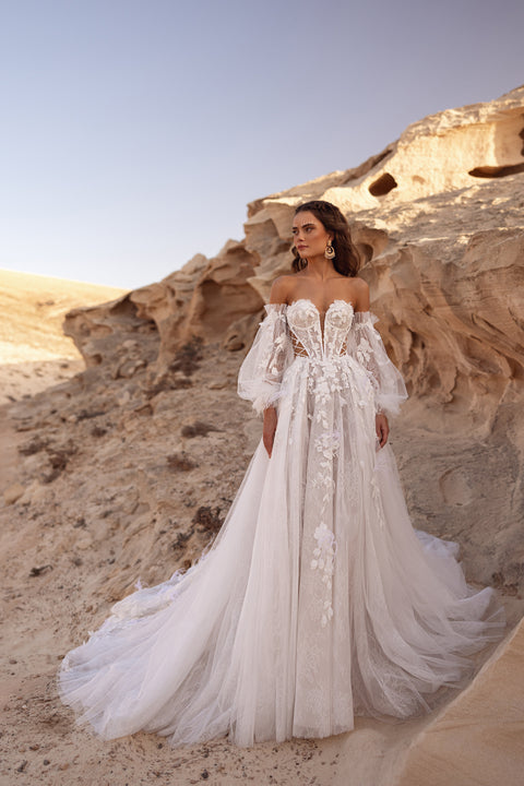 The Huda bridal gown with off-the-shoulder neckline, floral appliqué and corset detailing embodies romantic bohemian elegance.
