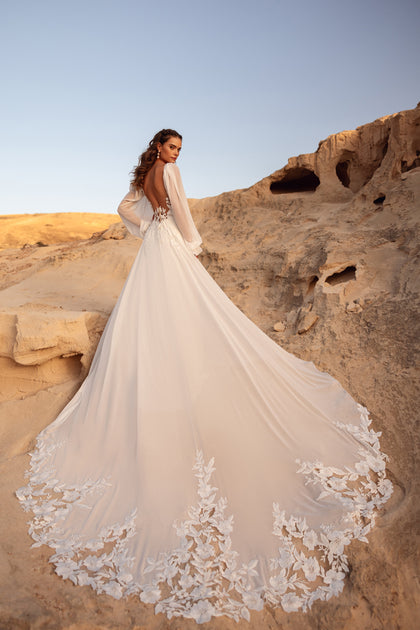 The Judith wedding gown with an open back and floral lace details offers a sensual yet sophisticated bridal look.