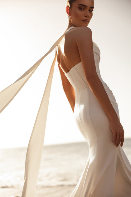 The Luna bridal dress with a long elegant train and soft ribbons moves beautifully in the sea breeze.