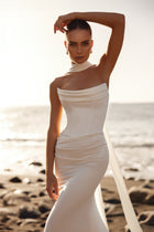 The Luna bridal gown showcases a slim silhouette and flowing train, ideal for a contemporary seaside ceremony.