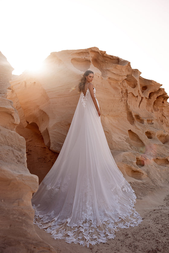 Malika sheer bridal cape with floral appliqué and illusion lace bodice for a modern romantic wedding style.