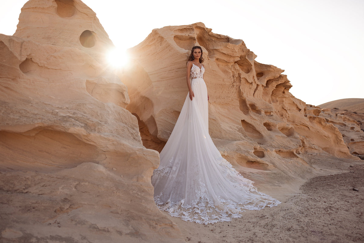 Wide horizontal view of Malika wedding dress and its flowing skirt in a rocky landscape