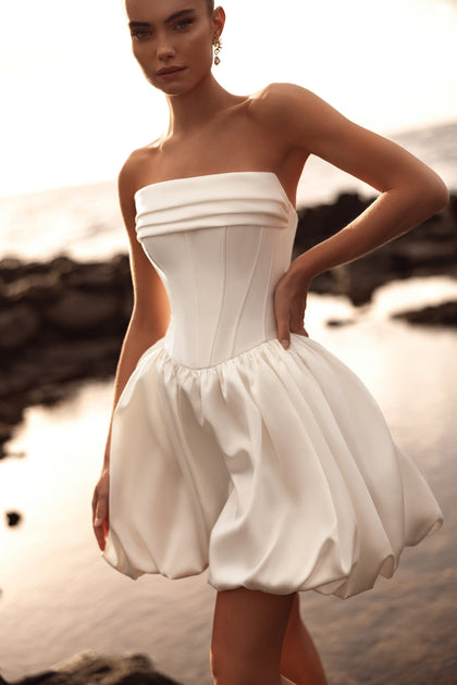 Martini mini bridal gown featuring a corset bodice and voluminous bubble skirt offers a fresh and contemporary bridal look.