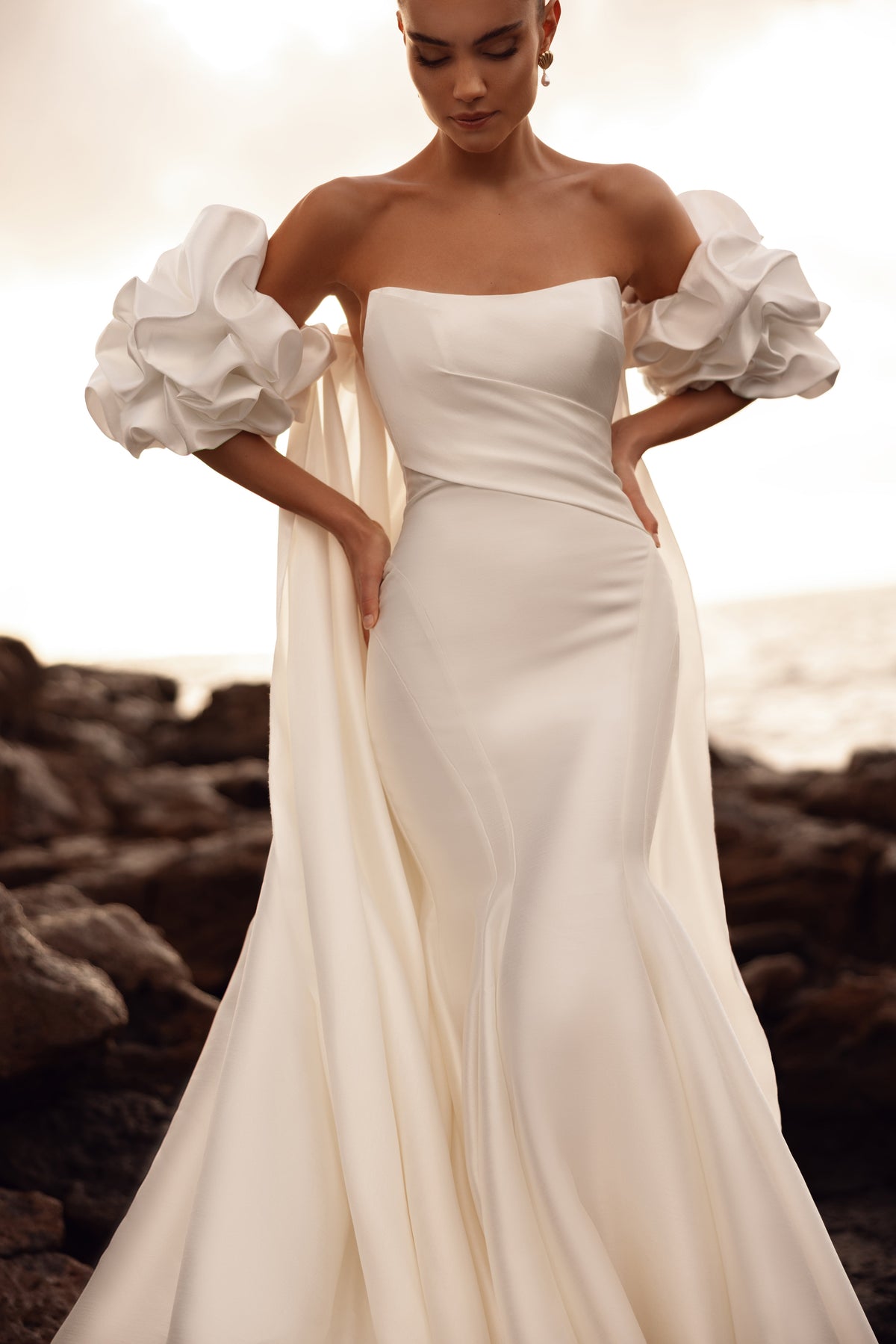 Mermaid wedding dress with off-the-shoulder puff sleeves and a structured bodice accentuating the waist.