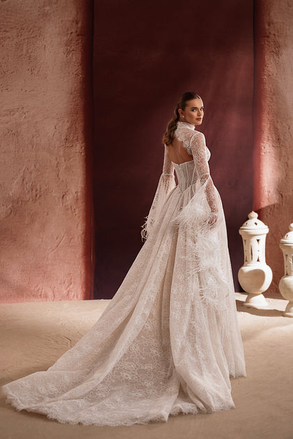 The Michelle bridal gown with a high lace neckline, flowing train, and feather accents defines luxury and sophistication.