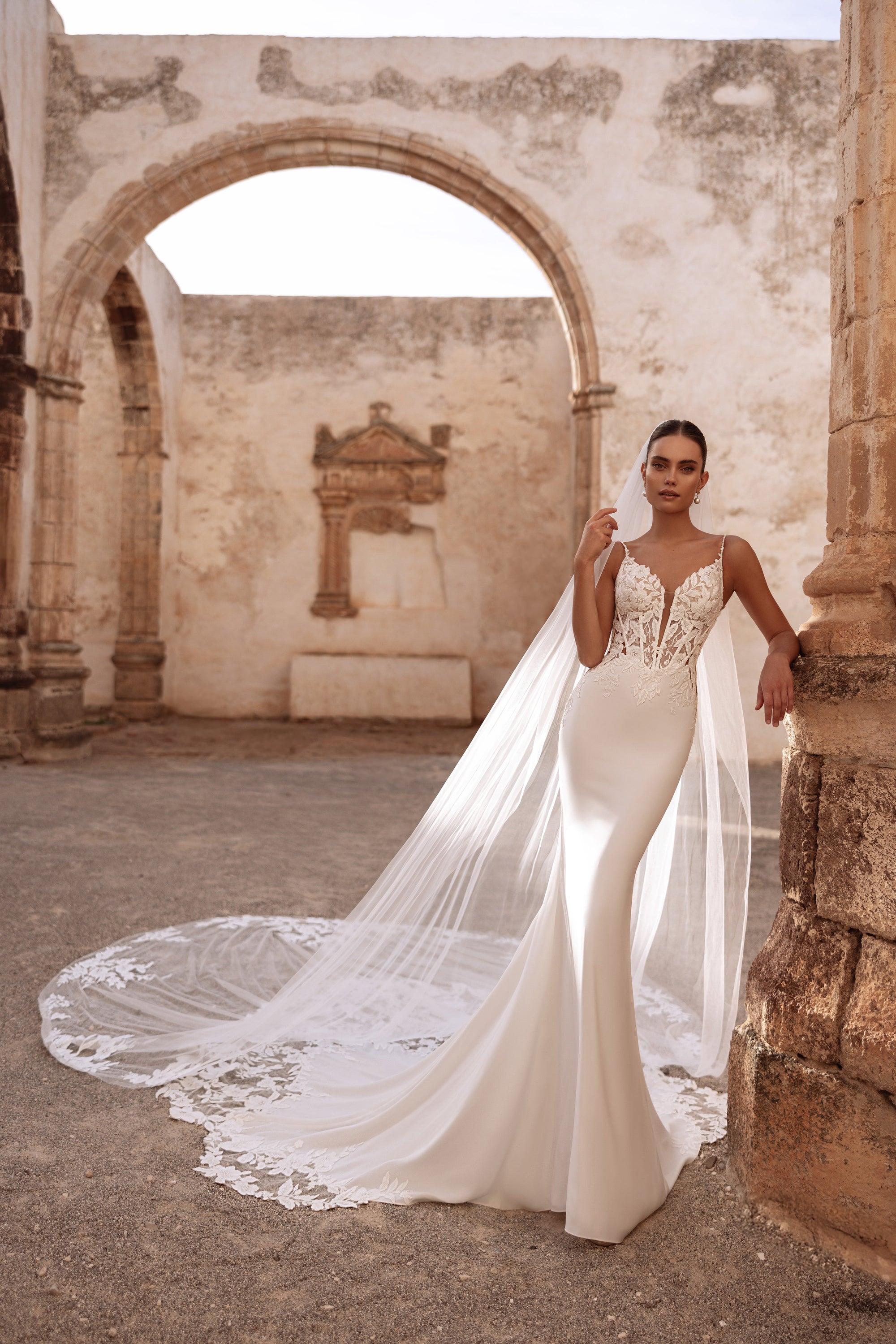 The Munira wedding veil with lace appliqués beautifully complements the gown, adding a romantic and ethereal touch.