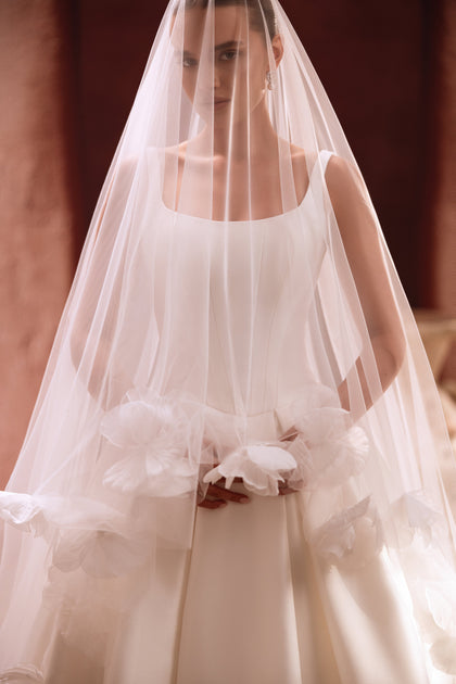 The Nicolette bridal dress with a tulle veil featuring large floral motifs combines artistry with bridal elegance.