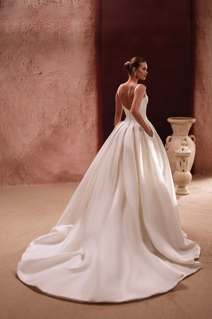The Nicolette bridal dress with a flowing train and structured bodice captures regal elegance and sophistication.