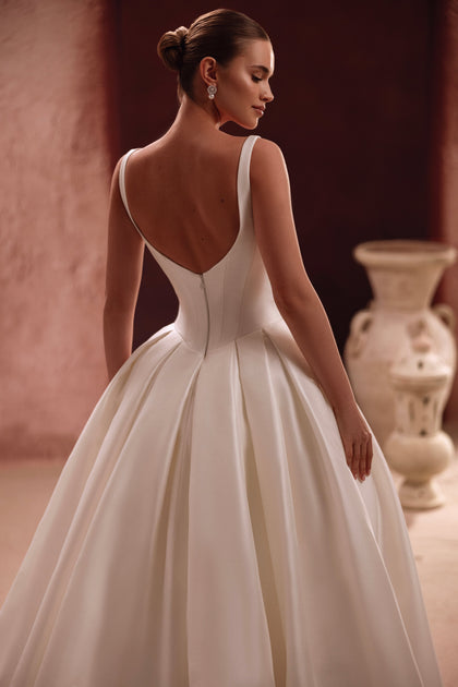 The Nicolette bridal gown’s deep V-back creates a romantic silhouette with modern minimalist charm.