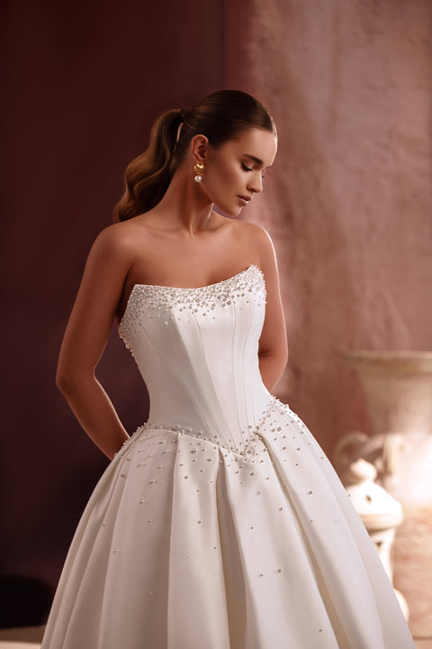 The Noor princess-style bridal gown featuring a strapless bodice and delicate pearl details captures classic sophistication.